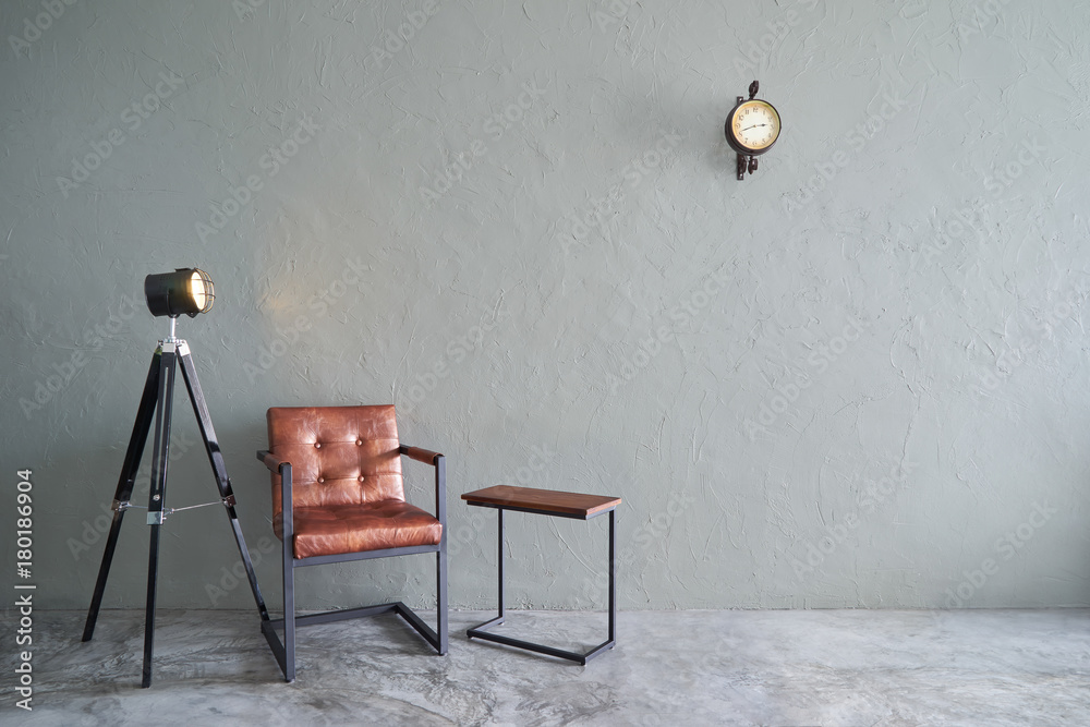 Modern living room with brown iron chair , clock ,tea table and lamp stand. cement floor and concrete wall ,Interior design with Loft style .