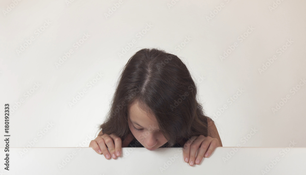 Beautiful girl teenager looks at a poster with information on white background Beautiful girl teenager looks at a poster with information on white background