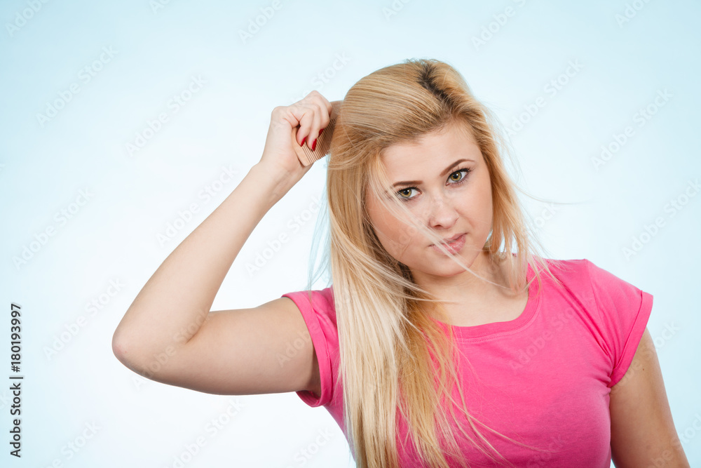 Woman brushing her long blonde hair with comb Woman brushing her long blonde hair with comb