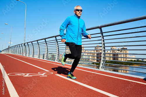 Healthy and active mature man jogging in the morning in urban environment © pressmaster