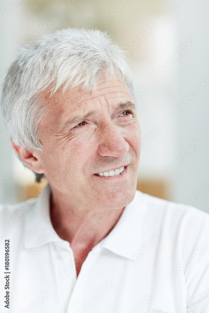 Senior man with toothy smile and grey hair staring aside at something curious Senior man with toothy smile and grey hair staring aside at something curious
