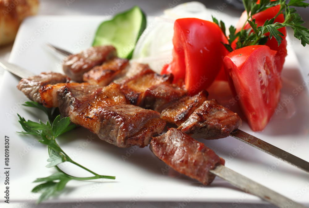 Kebab of beef with mutton fat,marinated in wine vinegar.Served with greens and tomatoes.Uzbek cuisine.