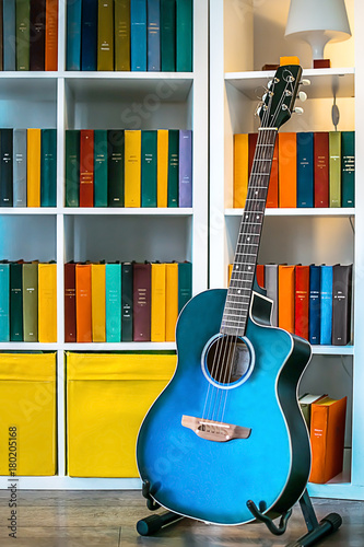 A blue guitar and a white shelf with books and a lamp