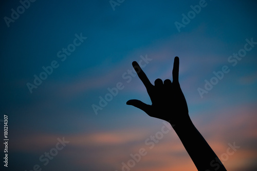 Silhouette of asian woman make hand say hi on sunset