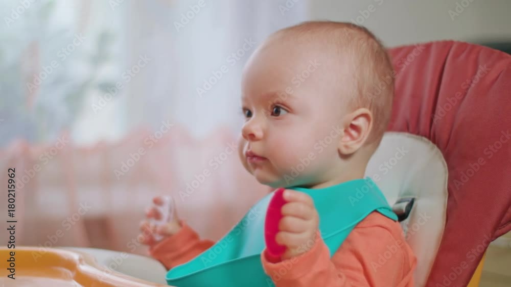 A baby girl eating puree at home. Medium shot. Soft focus. A baby girl eating puree at home. Medium shot. Soft focus.