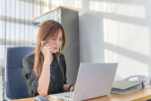 Asian officer woman talk phone and working with laptop on desk in the office