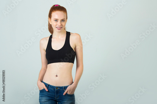 beautiful slender girl with a smile with red hair in sportswear on a light background