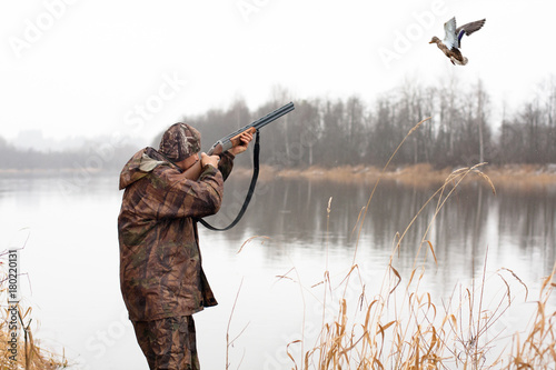 Photographie hunter shooting to the flying duck
