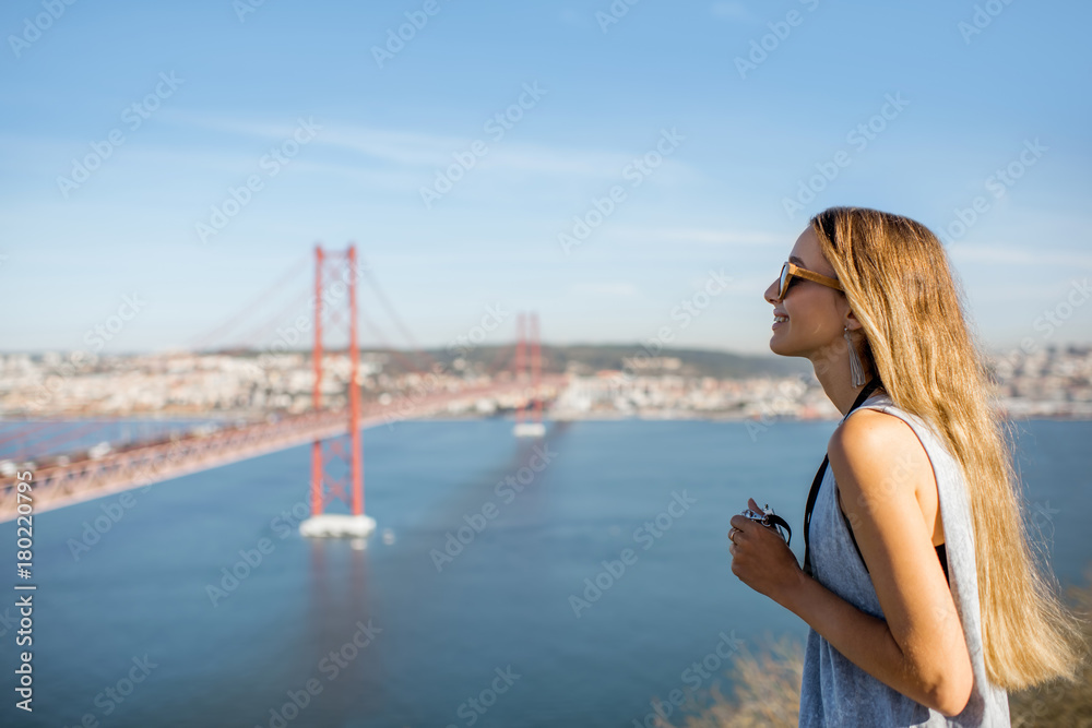 Young woman tourist enjoying beautiful aerial landscape view on the famous iron bridge in Lisbon city, Portugal