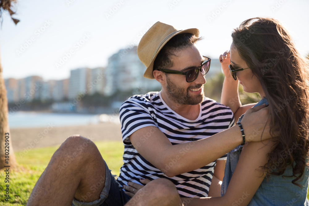 Happy young man sitting outside with girlfriend touching her