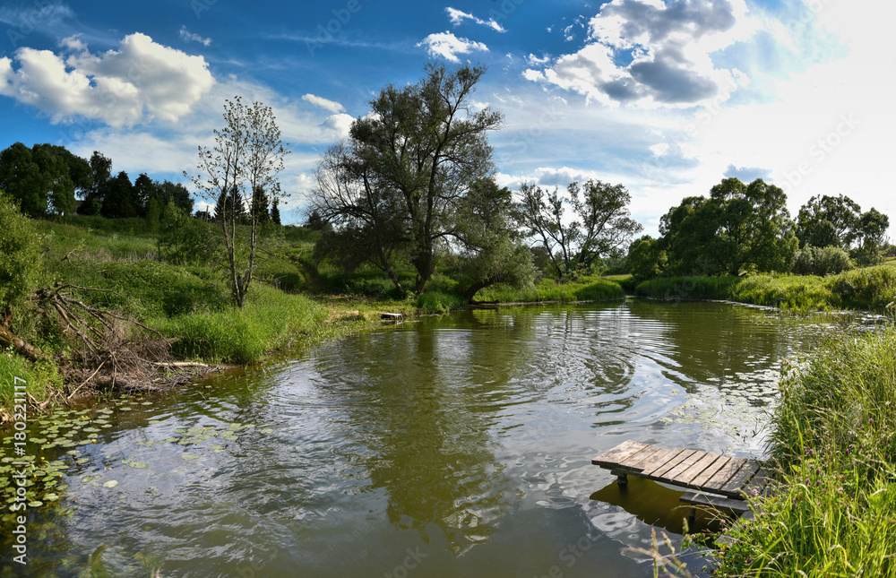 Pier on a calm river in the summer. Wooden pier bridge in the morning. Place for fishing in the river.