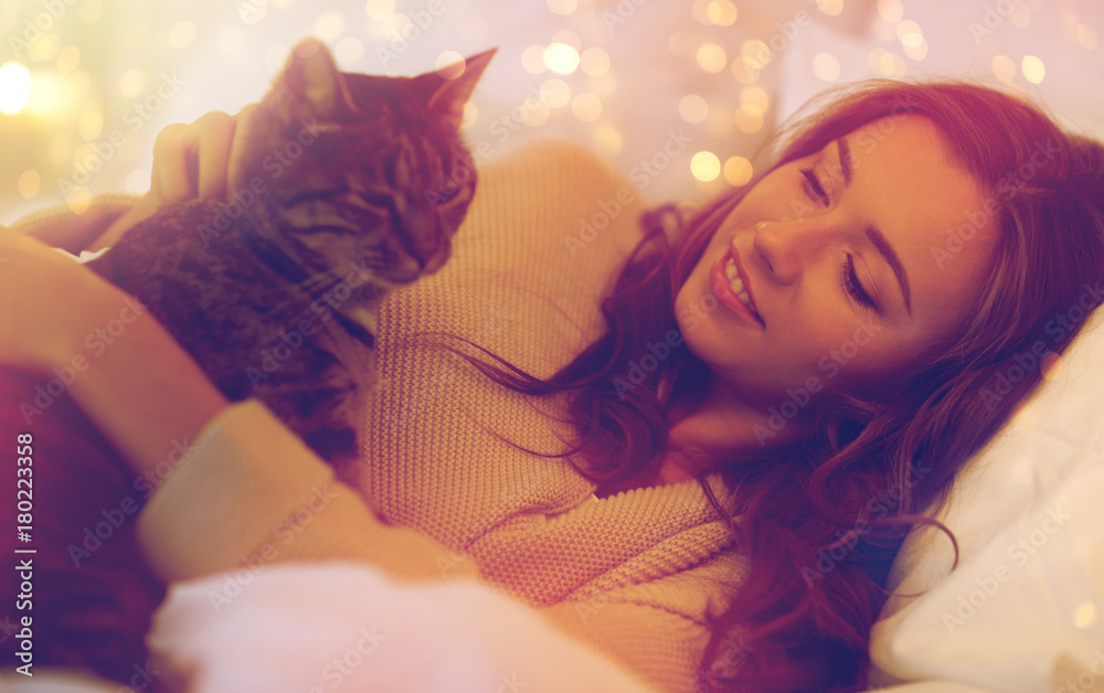 happy young woman with cat lying in bed at home happy young woman with cat lying in bed at home