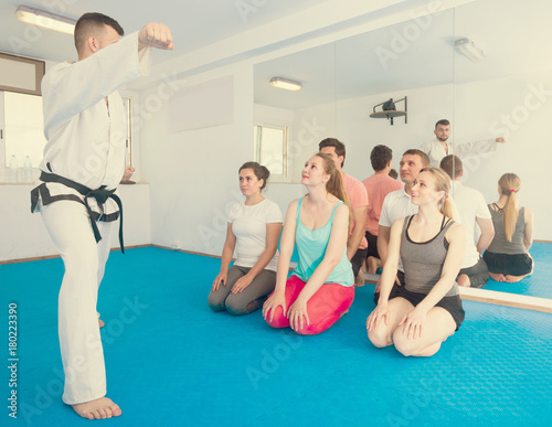 Young instructor is showing new martial moves to adults