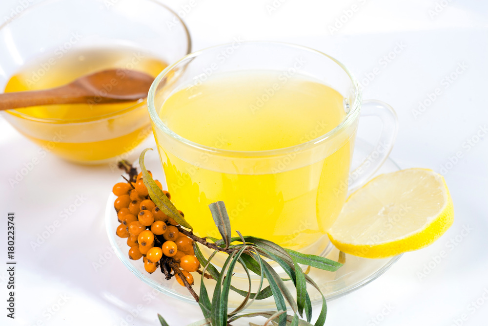 Healing sea-buckthorn tea delicious aromatic full of vitamin and microelements of bright yellow color with berries and leaves of the sea buckthorn fruit on a white background. Healing sea-buckthorn tea delicious aromatic full of vitamin and microelements of bright yellow color with berries and leaves of the sea buckthorn fruit on a white background.