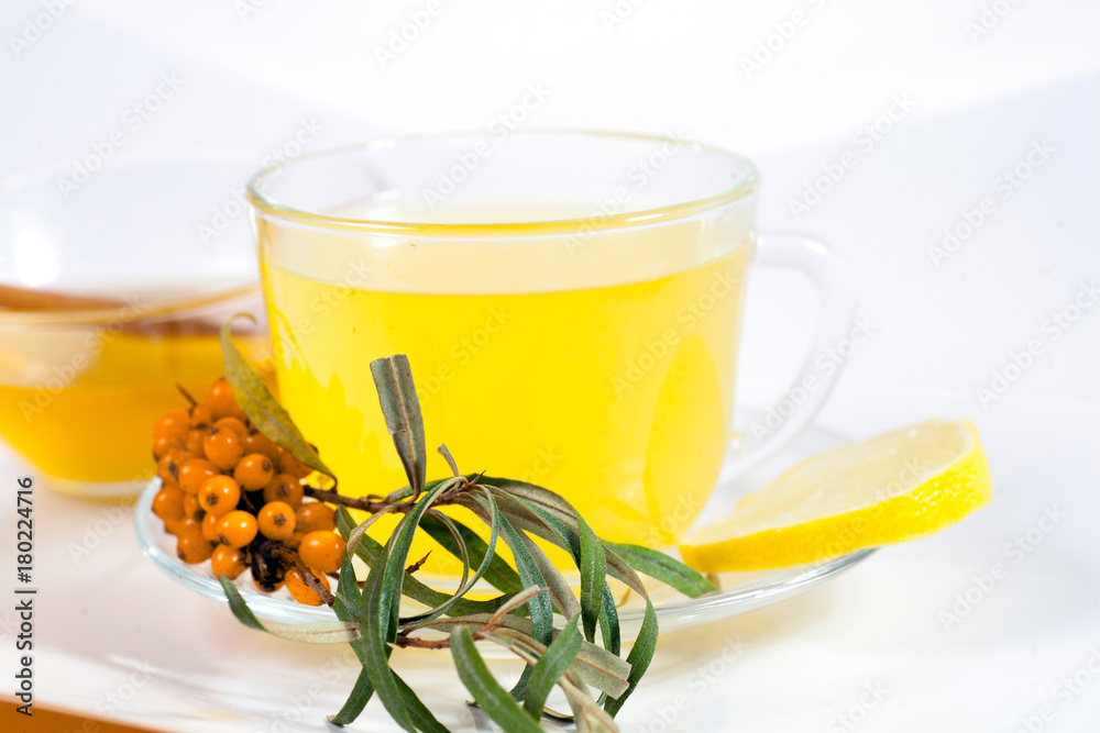 Healing sea-buckthorn tea delicious aromatic full of vitamin and microelements of bright yellow color with berries and leaves of the sea buckthorn fruit on a white background.