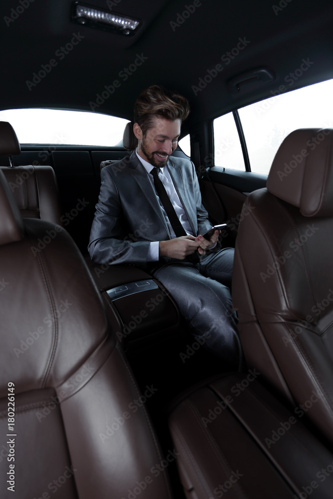 man in suit sitting in car and reading messages on smartphone man in suit sitting in car and reading messages on smartphone