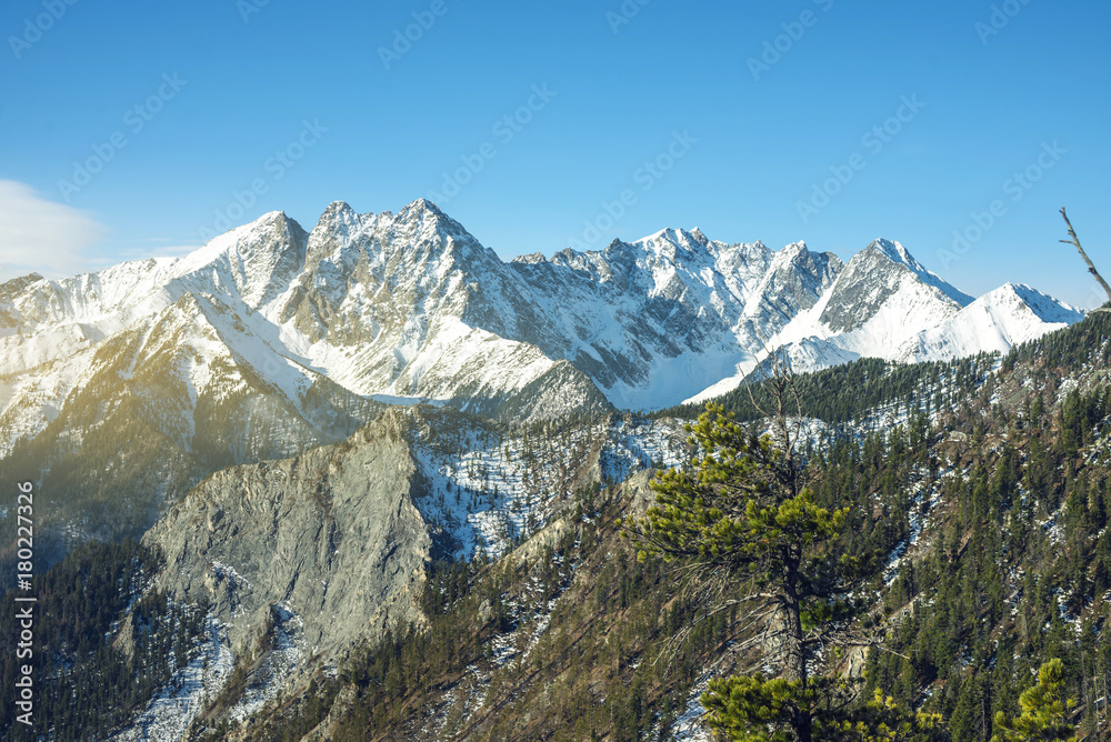 Beautiful view of the mountain peaks of the Baikal mountains in the snow at sunrise. Concept of travel and Hiking trips