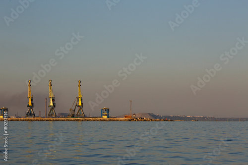 Many big cranes silhouette in the port at golden light of sunset. Mariupol, Ukraine