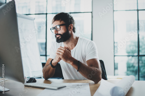 Wallpaper Mural Young professional bearded designer wearing eye glasses working at modern loft studio-office with desktop computer.Blurred background. Horizontal. Torontodigital.ca