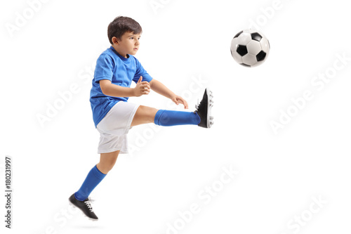 Little soccer player kicking a football in mid-air