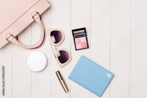Women cosmetics and fashion items on table with camera and passport. Top view