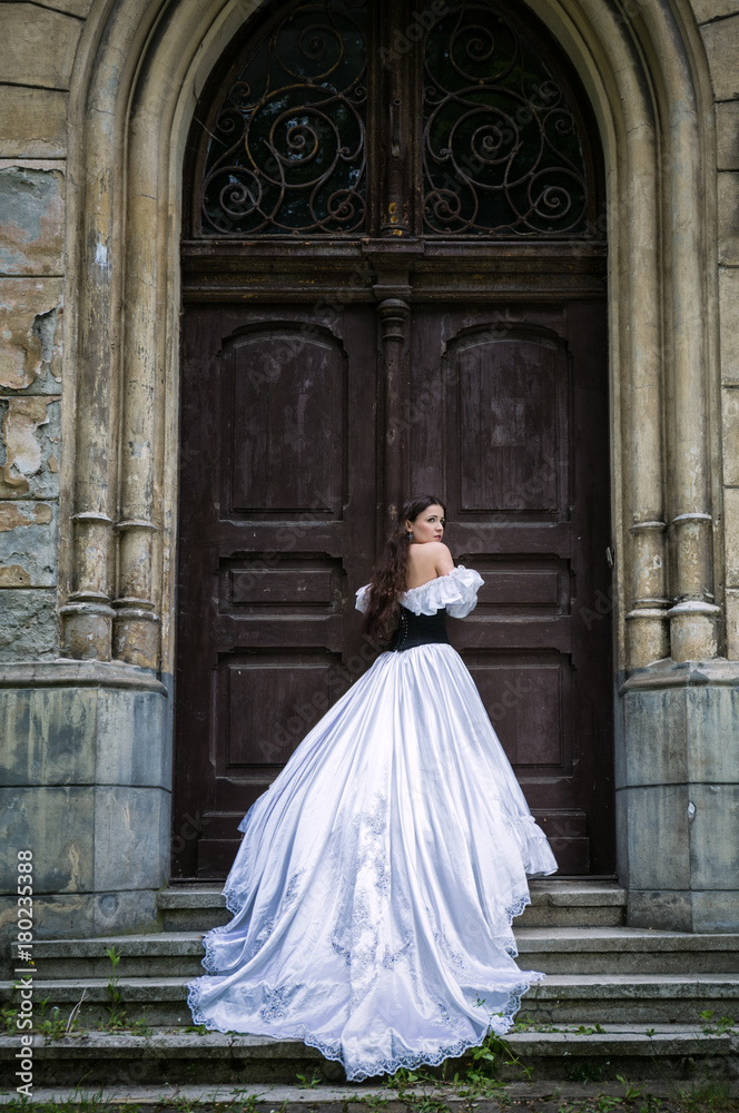 Woman in white Victorian dress with old door