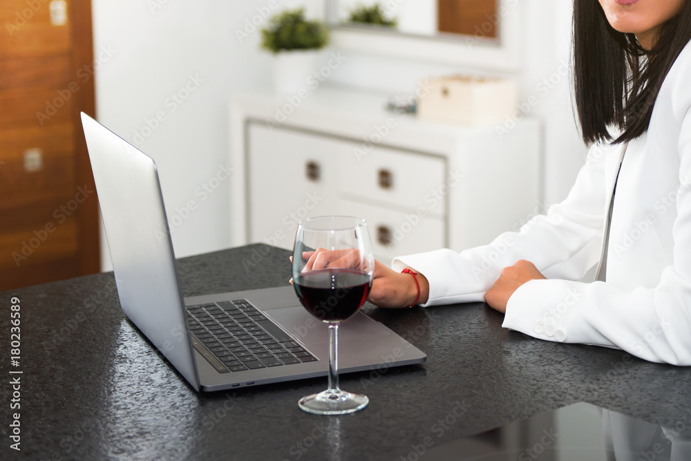 Beautiful young girl with a laptop and a wine glass