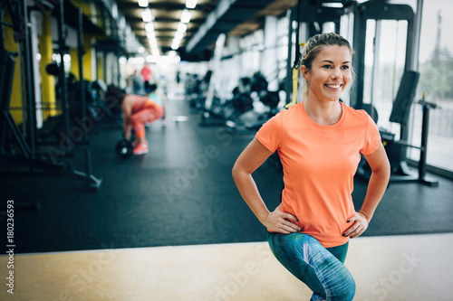 Young smiling sporty woman stretching in gym
