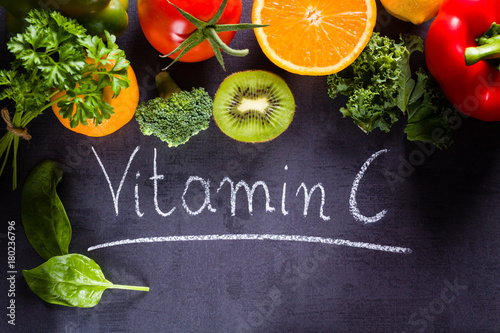 Fruits and vegetables rich in vitamin c with white word inscription by chalk.