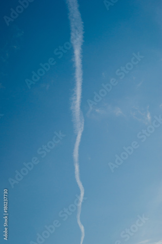 Vertical track in the sky from a flying airplane on a clear sunny day