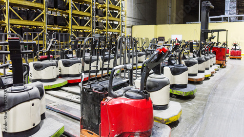 Forklifts or pallet jacks in a warehouse with batteries on racks