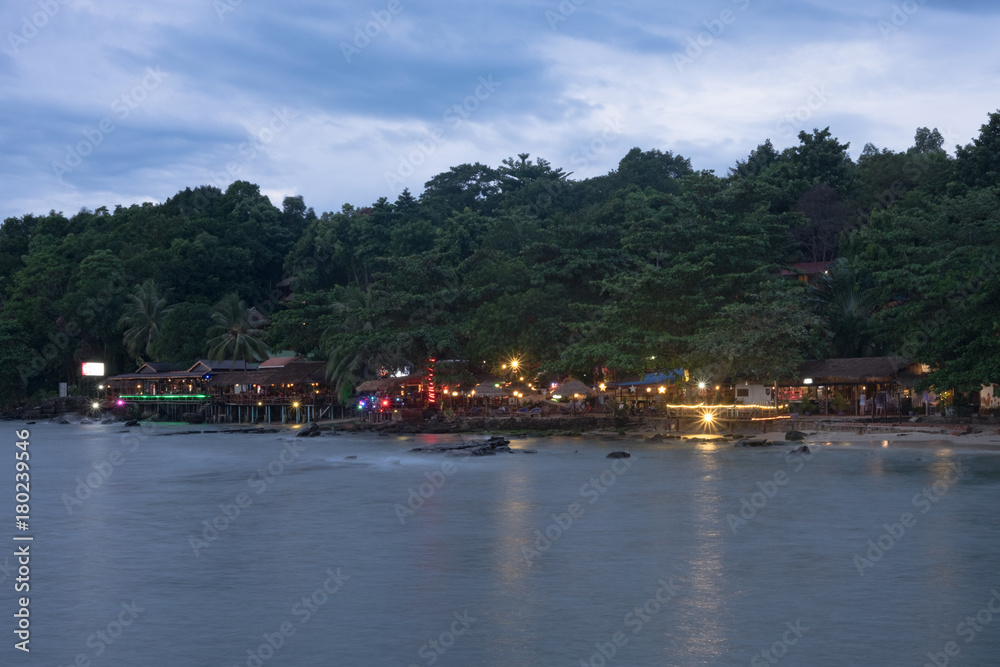 Colorful light of restaurants on the beach in Cambodia at evening with reflection in the water