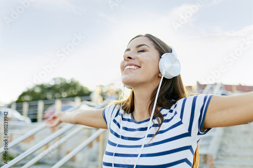 Happy young woman wearing headphones enjoying the summer photo