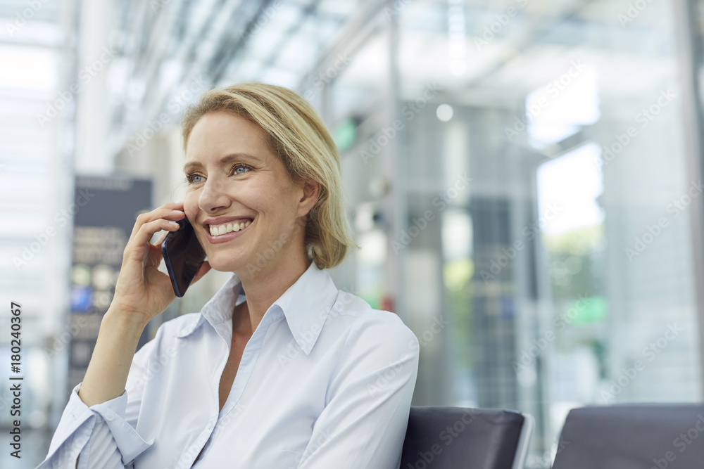 Portrait of laughing businesswoman on the phone waiting at the airport Portrait of laughing businesswoman on the phone waiting at the airport