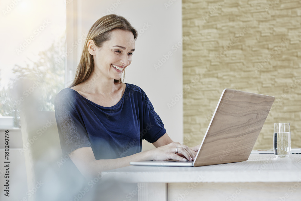 Happy woman using a laptop while sitting at home Happy woman using a laptop while sitting at home