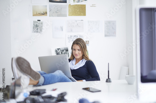 Smiling young woman using laptop at desk in office