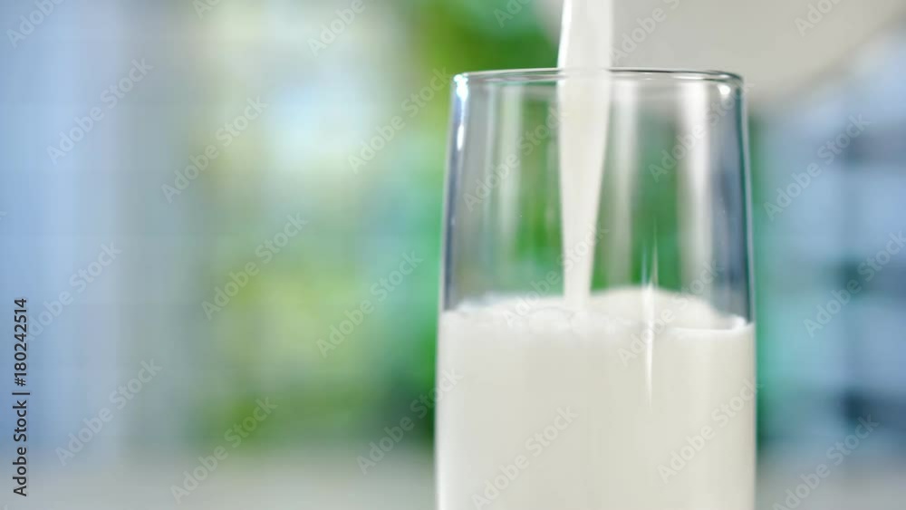 Close-up pouring fresh milk from the jug on table