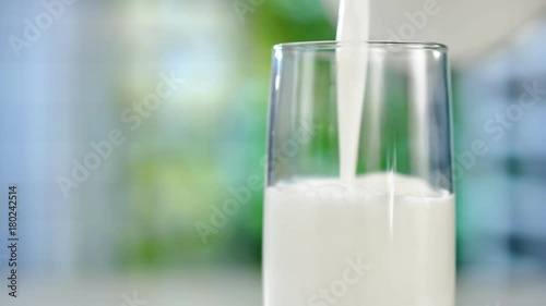 Close-up pouring fresh milk from the jug on table photo