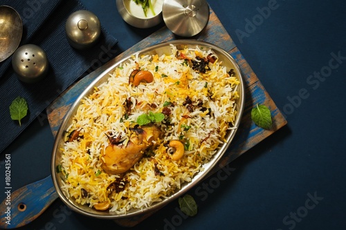 Homemade Chicken Dum Biryani served with raita, Overhead view on dark blue background photo