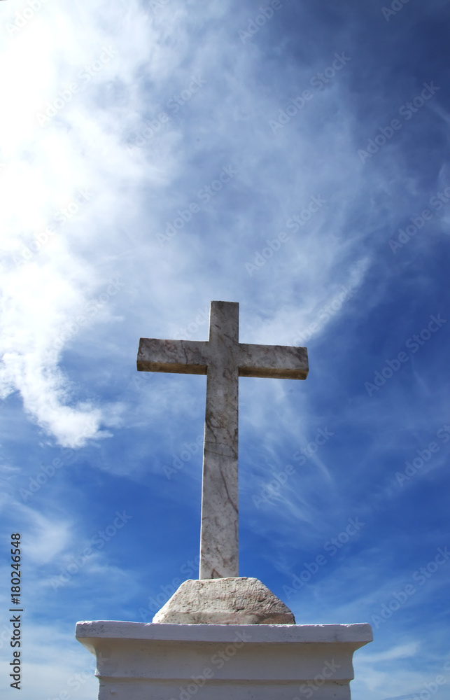 marble cross against blue sky with clouds