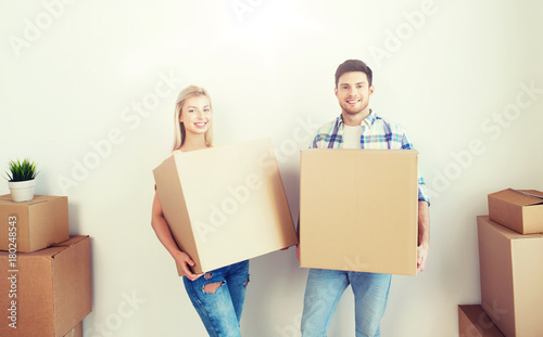 smiling couple with big boxes moving to new home