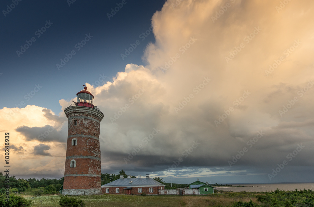 Lighthouse and house in the Baltic Sea. Shore, evening light, sunset, clouds and architecture concept. Mohni, small island in Estonia, Europe.