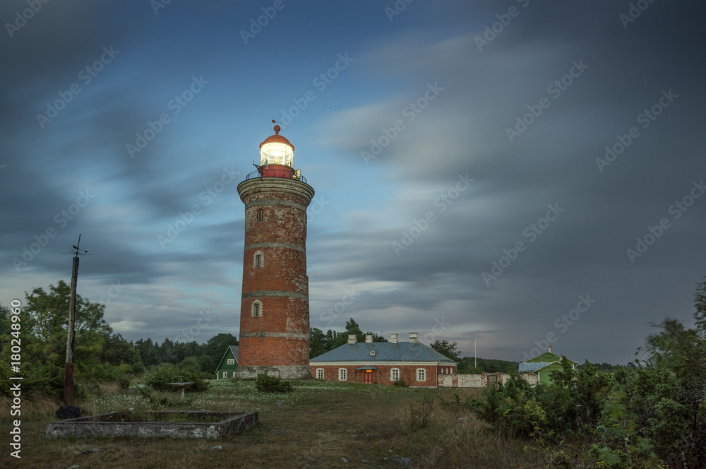 Lighthouse and house in the Baltic Sea. Shore, evening light, sunset, clouds and architecture concept. Mohni, small island in Estonia, Europe.