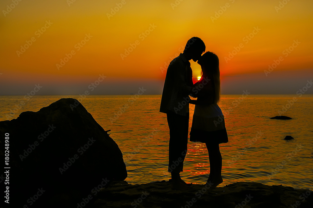 silhouette of a young couple on the beach against the background of dawn. The atmosphere of romance love.
