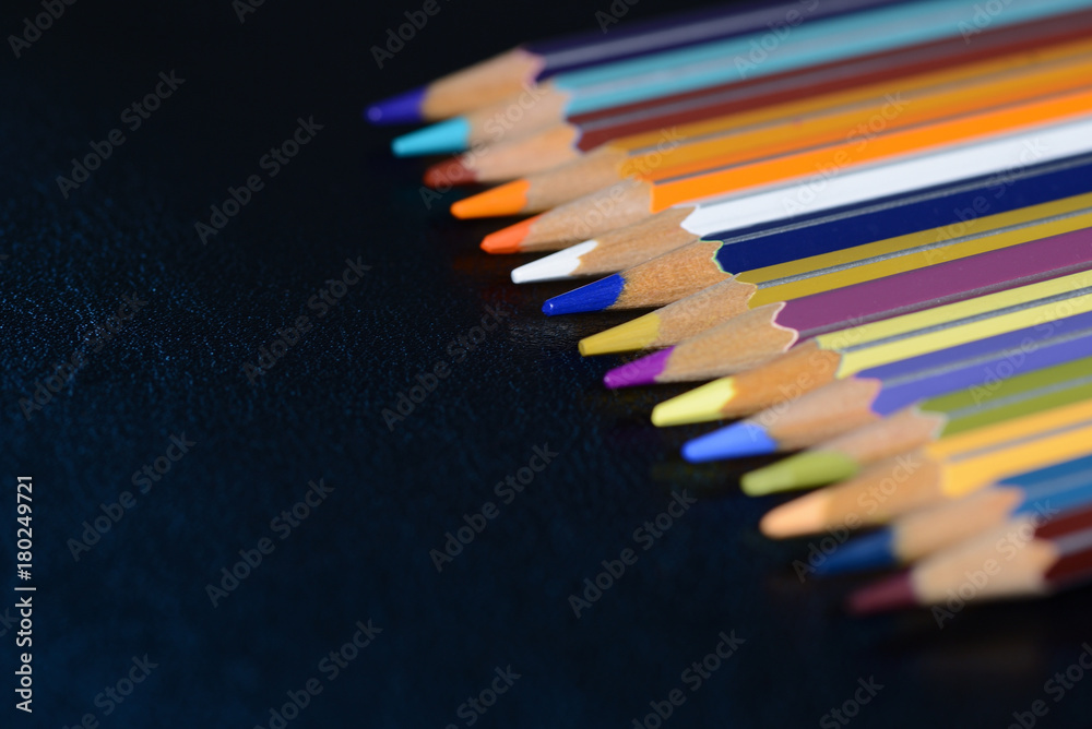 A pack of multicolored pencils on a dark gray background close up A pack of multicolored pencils on a dark gray background close up