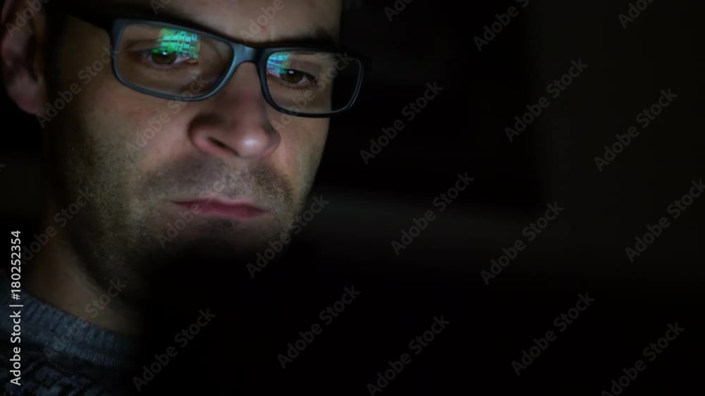 Gambling addicted man with glasses in front of online casino slot machine on laptop computer at night - loosing his money. Dramatic low light grain shot. Gambling addicted man with glasses in front of online casino slot machine on laptop computer at night - loosing his money. Dramatic low light grain shot.