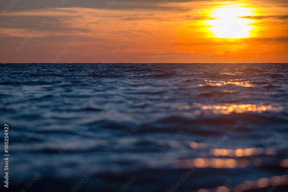 Obraz premium orange sun sets on the horizon of the sea