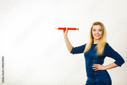 Positive woman holds big pencil in hand