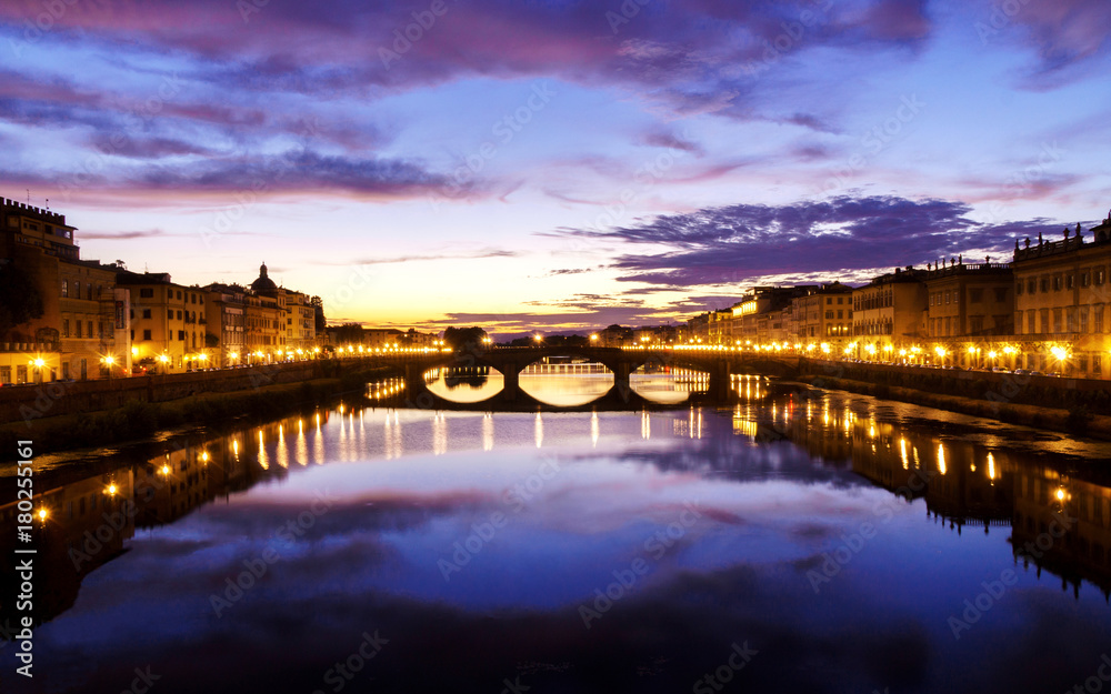 Late sunset time in Florence with street lights turned on and spectacular clouds over city and river.