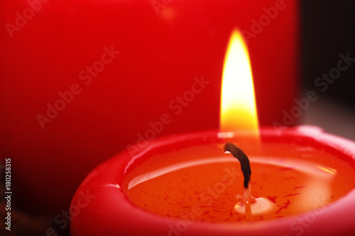 Closeup of red burning candles against black background .